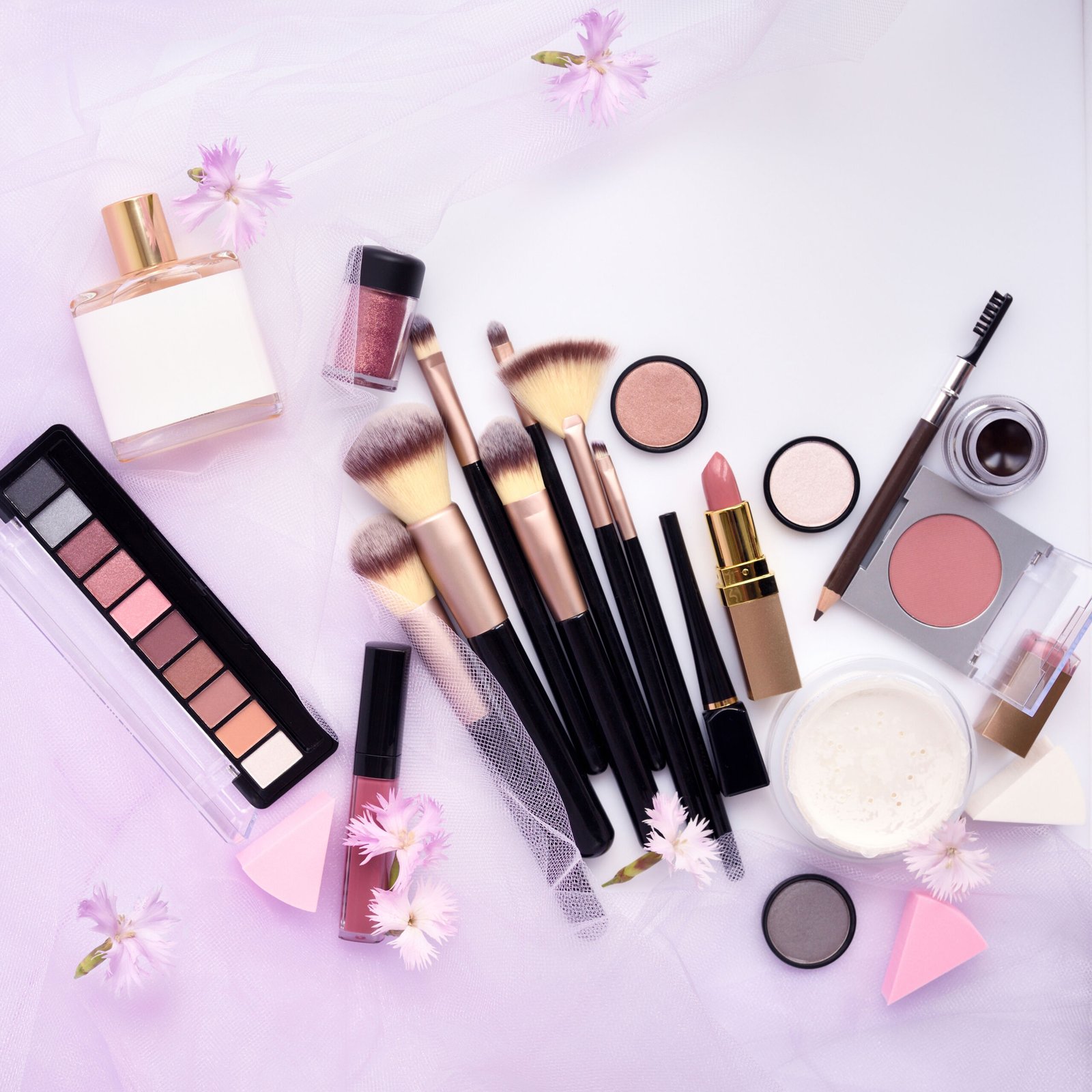 Makeup brush and decorative cosmetics with flowers on a pink veil background. Top view